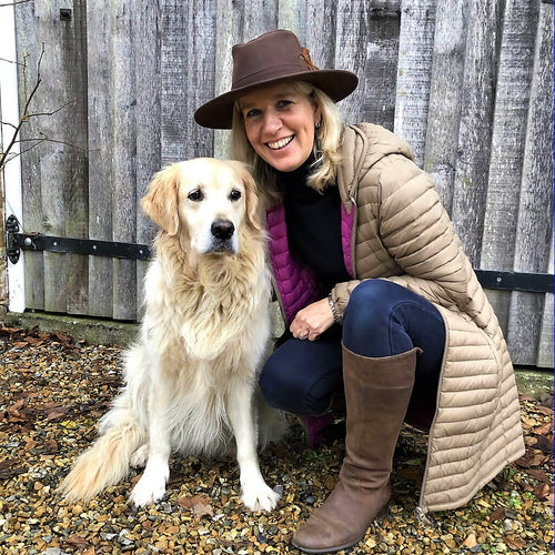 woman wearing brown fedora style wax explorer hat with feathers to one side of hat